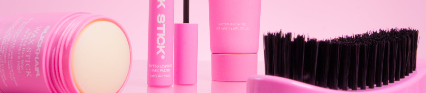 SLICKHAIR smoothing hairbrush, slick stick hair wand and open wax stick against a pink background.