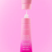 Upside down pink tube of SLICKHAIR Dream Cream on a pink background