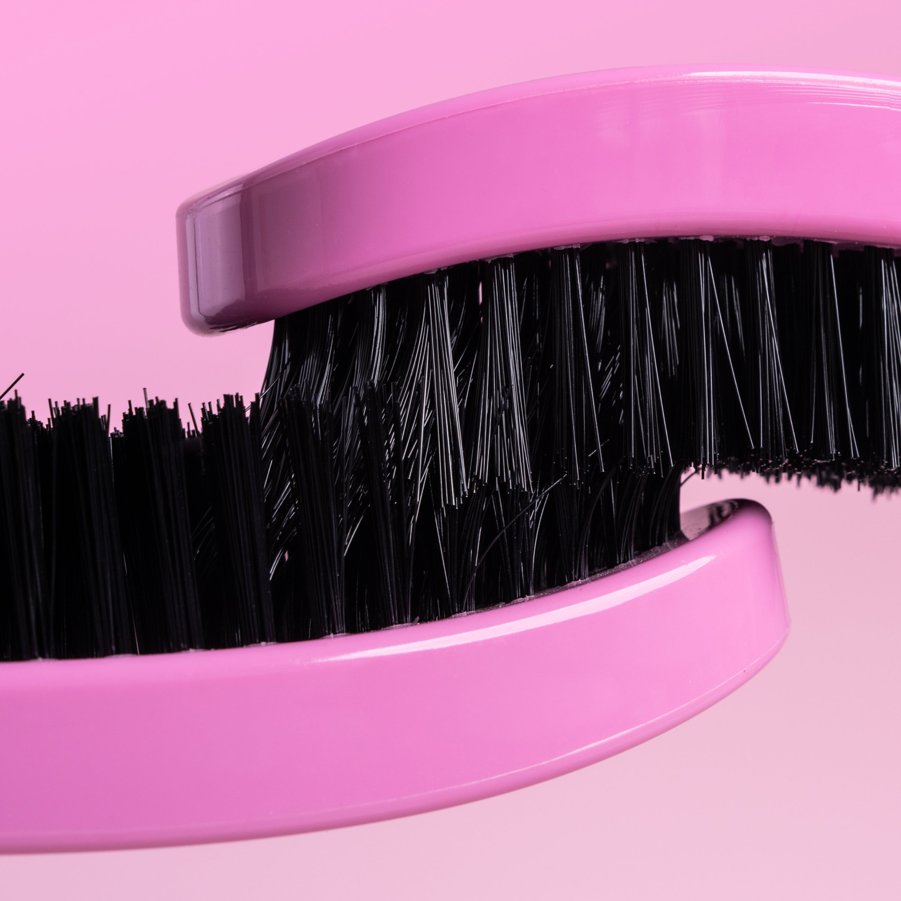Pink brush with black bristles on a pink background